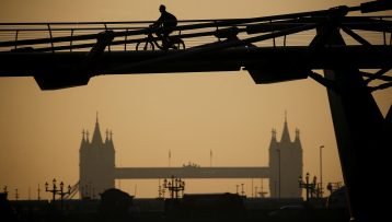 A person cycles across Millennium Bridge as the sun rises, in London, Britain, September 15, 2020. REUTERS/Henry Nicholls - RC2VYI9YSS3Z
